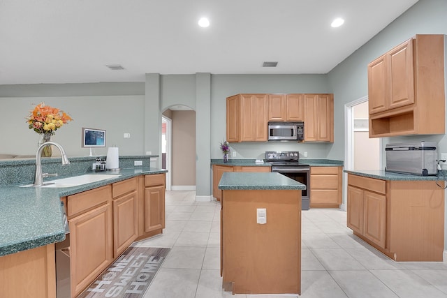 kitchen with visible vents, arched walkways, a center island, stainless steel appliances, and a sink