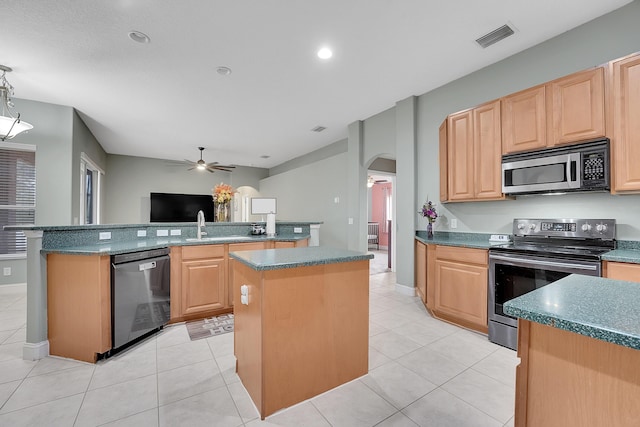 kitchen featuring visible vents, arched walkways, a kitchen island, stainless steel appliances, and light brown cabinets