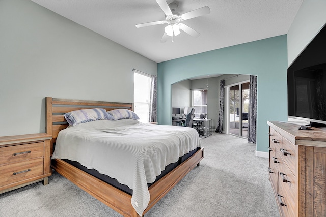 bedroom with access to exterior, arched walkways, light carpet, ceiling fan, and a textured ceiling