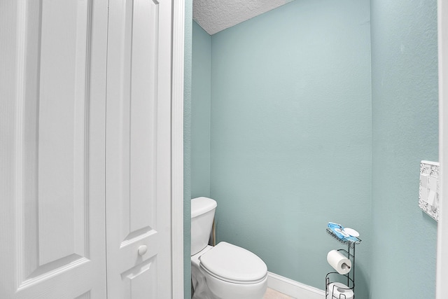 bathroom featuring baseboards, a textured ceiling, and toilet