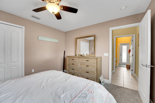 bedroom featuring a closet, visible vents, light carpet, and light tile patterned flooring