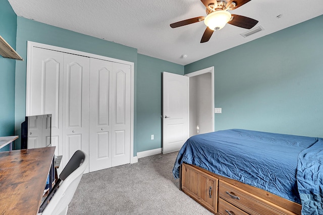 carpeted bedroom featuring a closet, visible vents, a ceiling fan, a textured ceiling, and baseboards