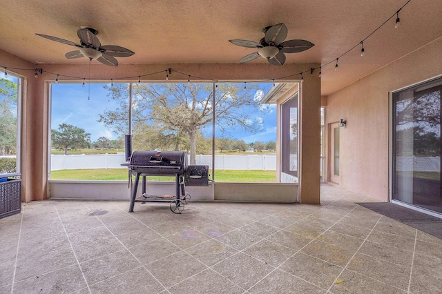 unfurnished sunroom featuring a water view, a healthy amount of sunlight, and a ceiling fan