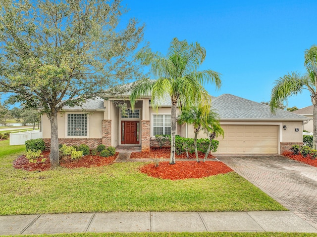 view of front of home featuring decorative driveway, brick siding, stucco siding, an attached garage, and a front lawn