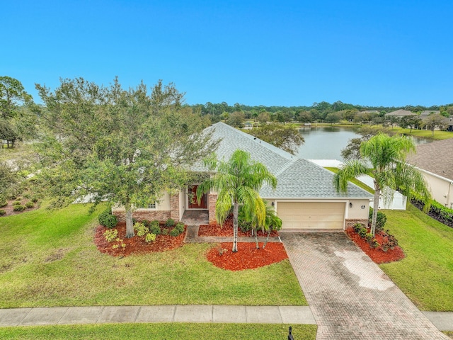 view of front facade with roof with shingles, a water view, an attached garage, decorative driveway, and a front yard