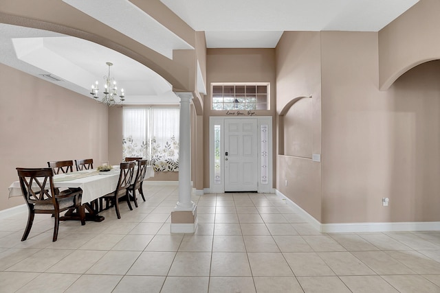 entryway featuring baseboards, decorative columns, an inviting chandelier, and light tile patterned floors