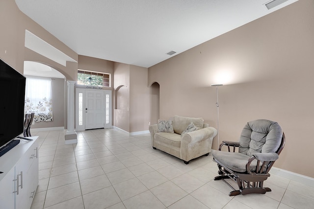 living area with arched walkways, visible vents, baseboards, and light tile patterned floors