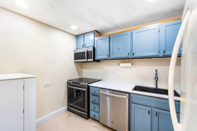 kitchen featuring blue cabinetry, appliances with stainless steel finishes, light tile patterned flooring, and sink