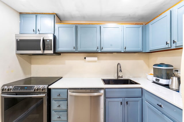 kitchen with blue cabinetry, stainless steel appliances, and sink