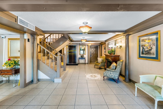 entrance foyer featuring beam ceiling, decorative columns, a textured ceiling, and light tile patterned flooring