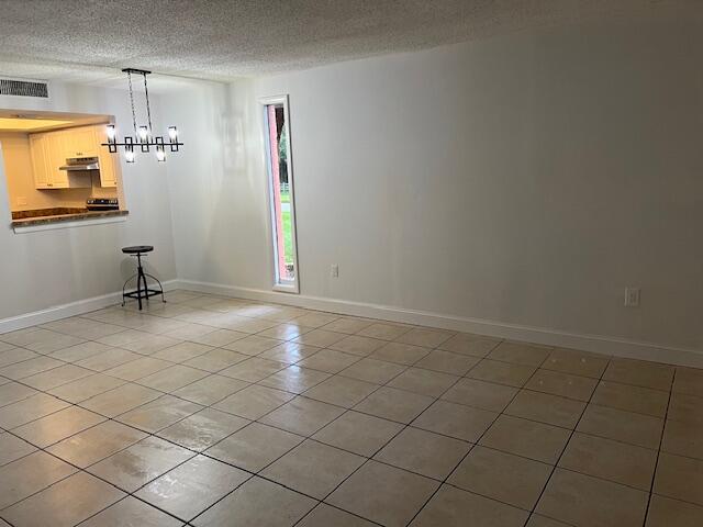 unfurnished dining area featuring light tile patterned floors, a notable chandelier, and a textured ceiling