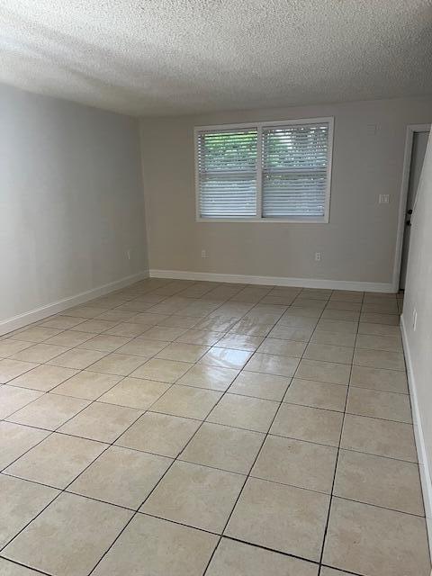 tiled empty room with a textured ceiling