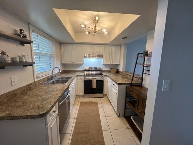 kitchen featuring a raised ceiling, white cabinetry, sink, light tile patterned floors, and stainless steel appliances