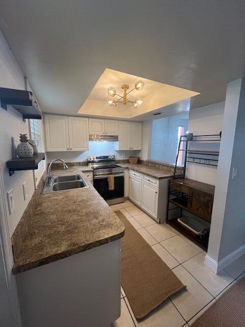 kitchen with sink, light tile patterned floors, white cabinetry, stainless steel range with electric cooktop, and a raised ceiling