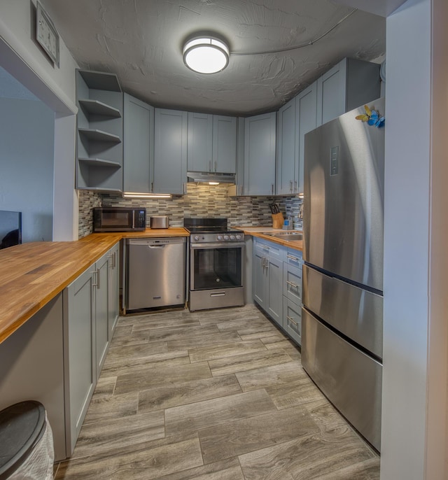 kitchen with stainless steel appliances, butcher block countertops, and backsplash