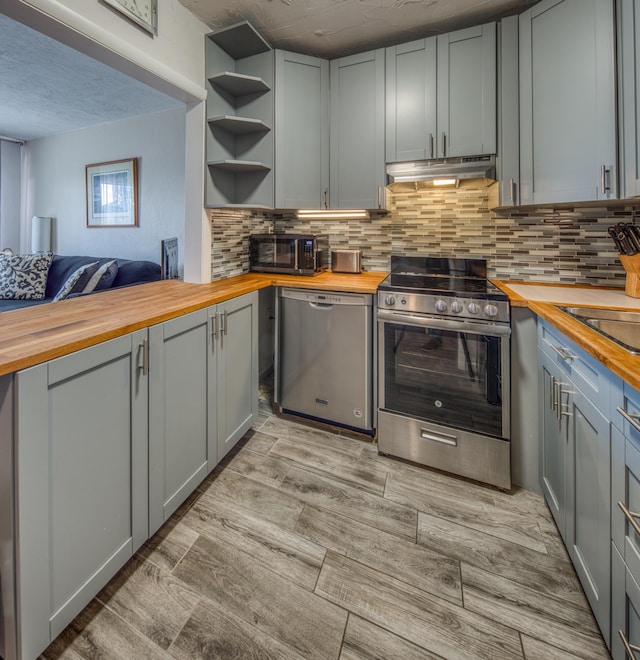 kitchen featuring butcher block counters, tasteful backsplash, stainless steel appliances, and gray cabinetry