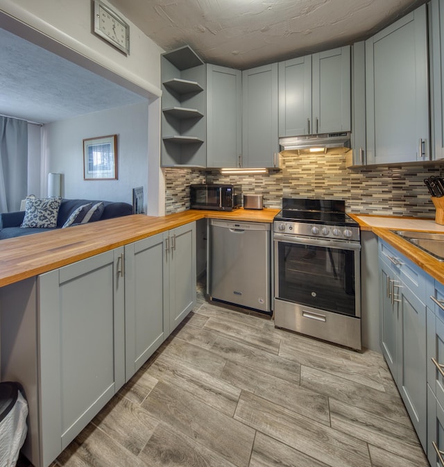 kitchen featuring wood counters, stainless steel appliances, sink, and decorative backsplash