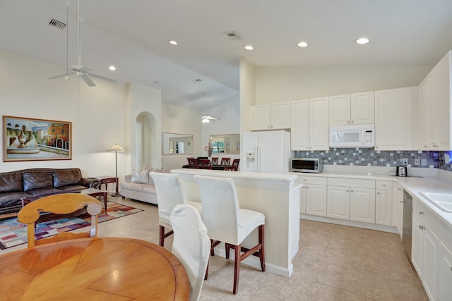 kitchen with a breakfast bar, ceiling fan, white cabinetry, stainless steel appliances, and tasteful backsplash