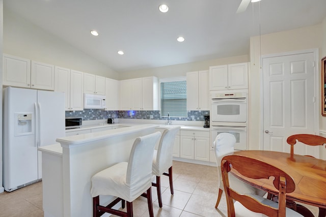 kitchen featuring light tile patterned floors, white appliances, white cabinetry, tasteful backsplash, and a kitchen island