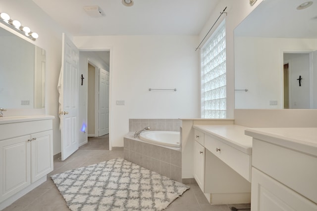 bathroom featuring a relaxing tiled tub, plenty of natural light, tile patterned flooring, and vanity