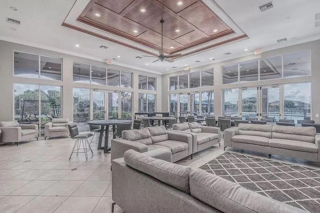 tiled living room with ornamental molding, a raised ceiling, and a wealth of natural light