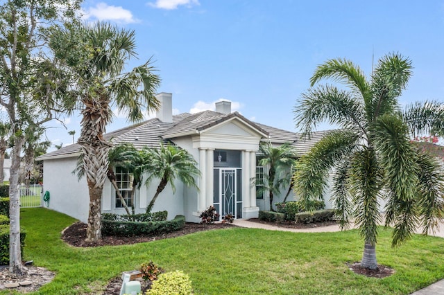 view of front facade with a front yard, a tiled roof, and stucco siding