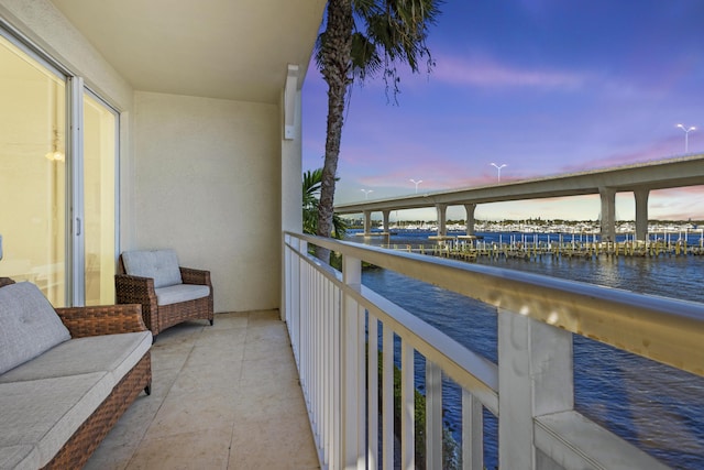 balcony at dusk featuring a water view