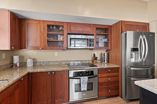 kitchen with brown cabinets, glass insert cabinets, stainless steel appliances, and light stone counters