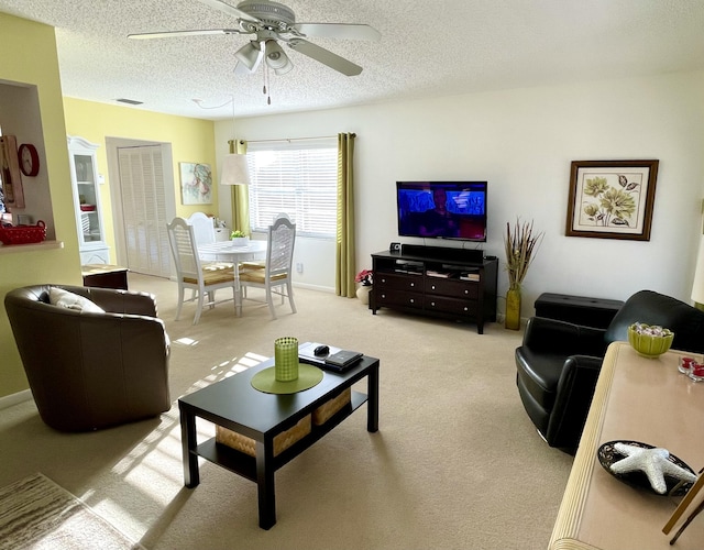 carpeted living room with ceiling fan and a textured ceiling