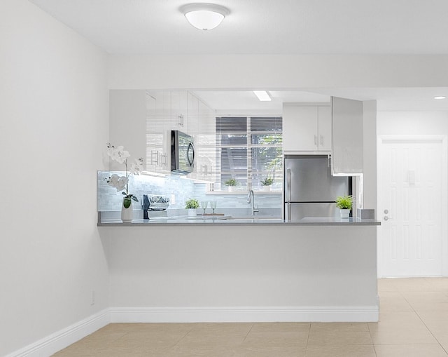 kitchen with white cabinetry, appliances with stainless steel finishes, light tile patterned floors, and kitchen peninsula