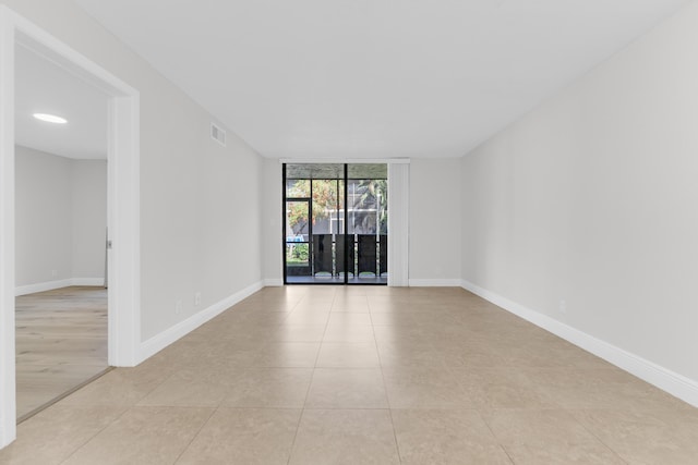 empty room featuring expansive windows and light tile patterned floors