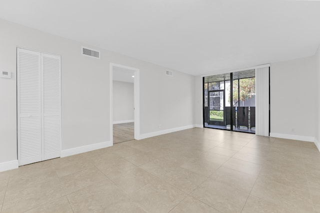 spare room featuring a wall of windows and light tile patterned flooring