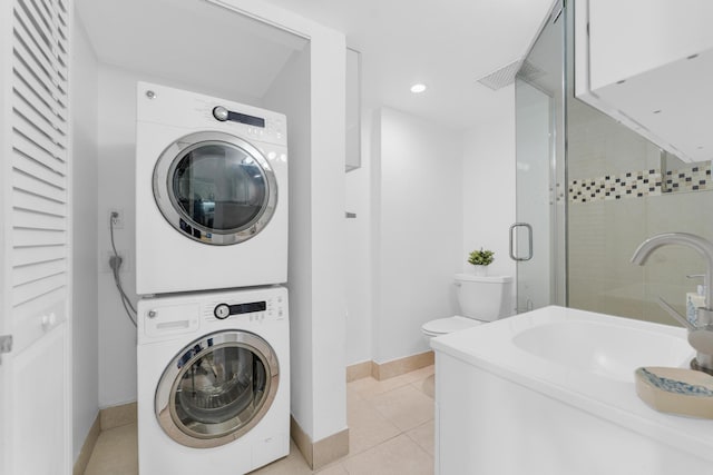 laundry area with stacked washer / drying machine, sink, and light tile patterned flooring