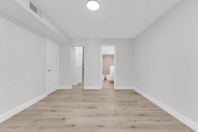 unfurnished bedroom with a closet, light wood-type flooring, and ensuite bath