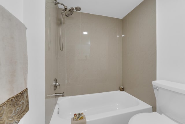 bathroom featuring tiled shower / bath combo and toilet