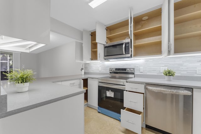 kitchen with stainless steel appliances, light countertops, white cabinetry, and open shelves