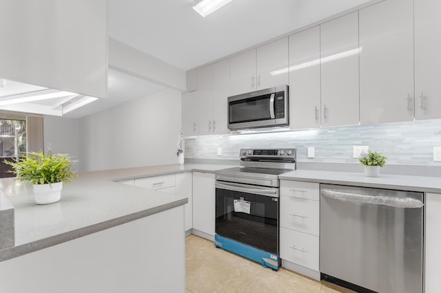 kitchen featuring light countertops, backsplash, appliances with stainless steel finishes, white cabinets, and a peninsula