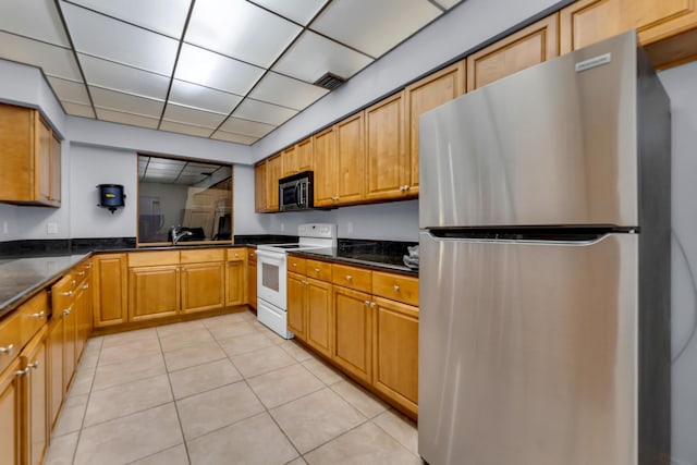 kitchen with sink, a paneled ceiling, light tile patterned flooring, and appliances with stainless steel finishes