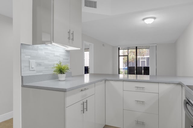 kitchen featuring white cabinetry, kitchen peninsula, and backsplash