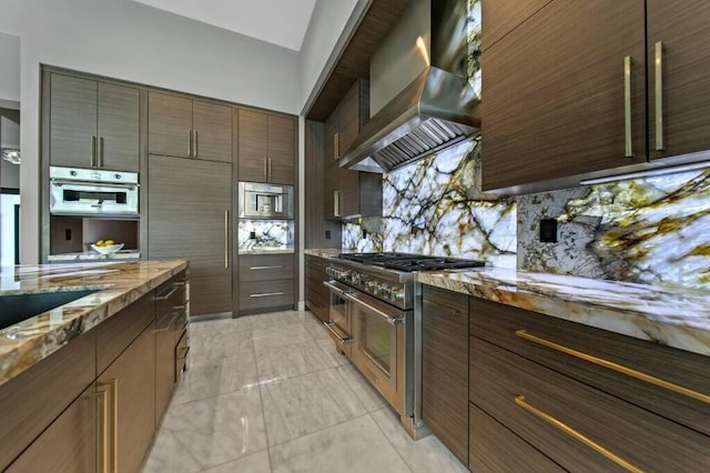 kitchen featuring stainless steel appliances, light stone countertops, backsplash, wall chimney range hood, and modern cabinets