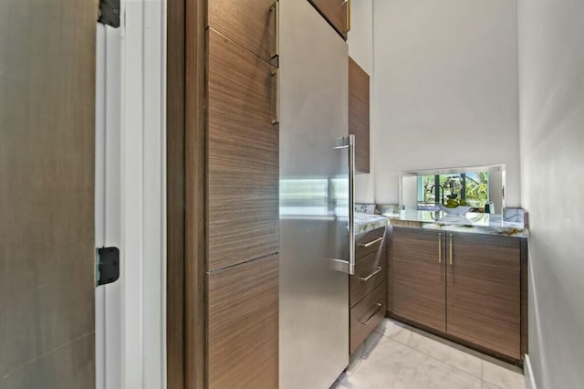 kitchen featuring light tile patterned floors, a high ceiling, modern cabinets, and brown cabinets