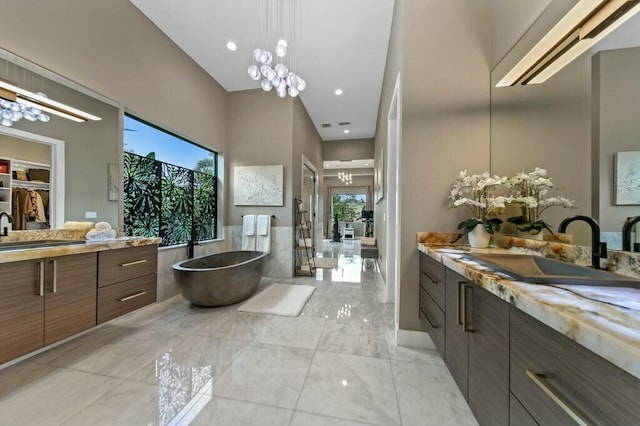 bathroom featuring a freestanding bath, two vanities, a sink, and a notable chandelier