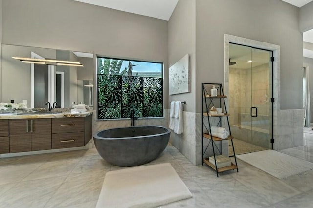 bathroom with a wainscoted wall, tile walls, a freestanding bath, a shower stall, and vanity