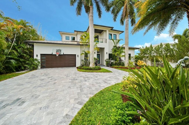 view of front of home with stucco siding, metal roof, decorative driveway, an attached garage, and a standing seam roof