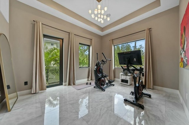 workout area featuring marble finish floor, baseboards, and a tray ceiling