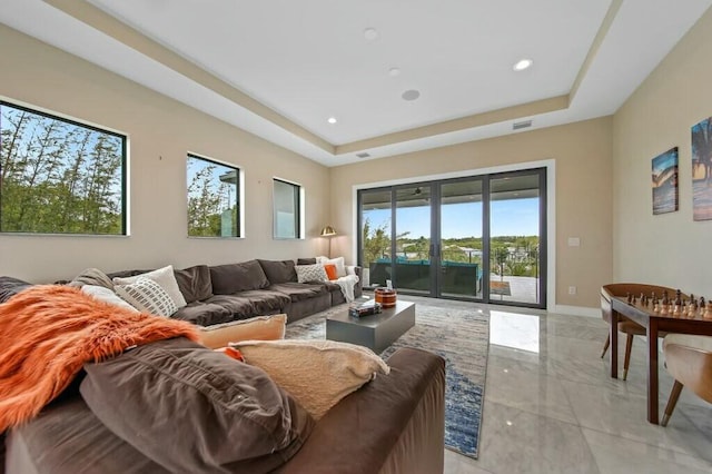 living room with marble finish floor, recessed lighting, a raised ceiling, and baseboards