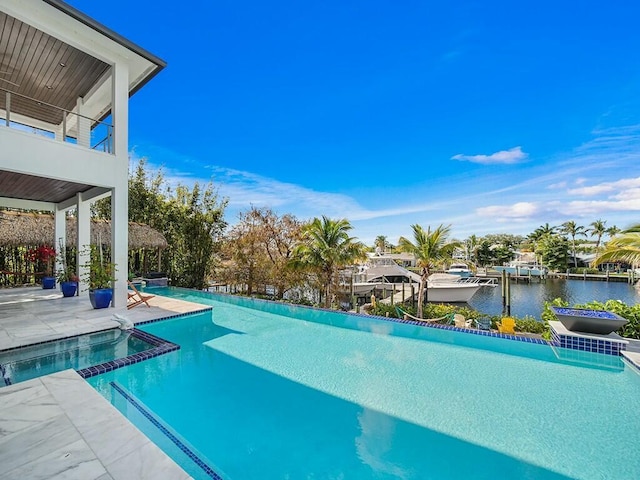 view of pool featuring a patio area, a pool with connected hot tub, and a water view