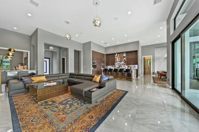 living room with marble finish floor, a towering ceiling, visible vents, and recessed lighting