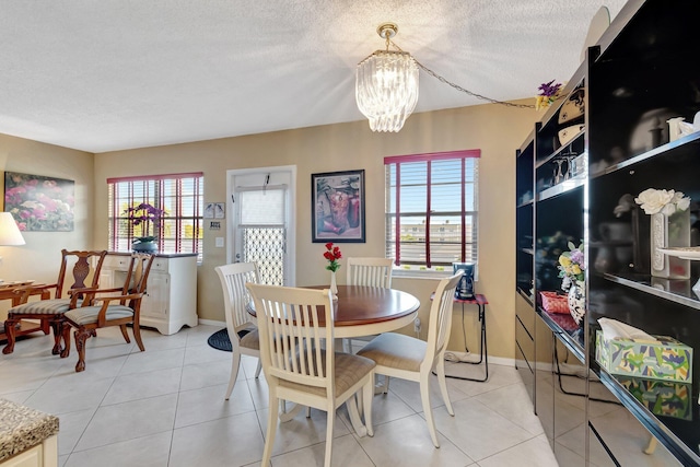 tiled dining room with plenty of natural light, an inviting chandelier, and a textured ceiling