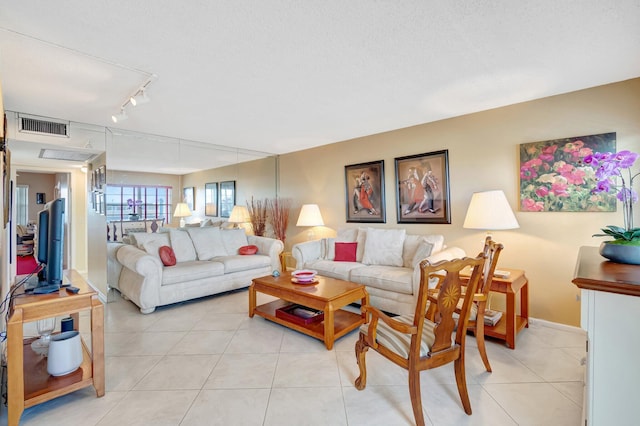 tiled living room featuring track lighting and a textured ceiling